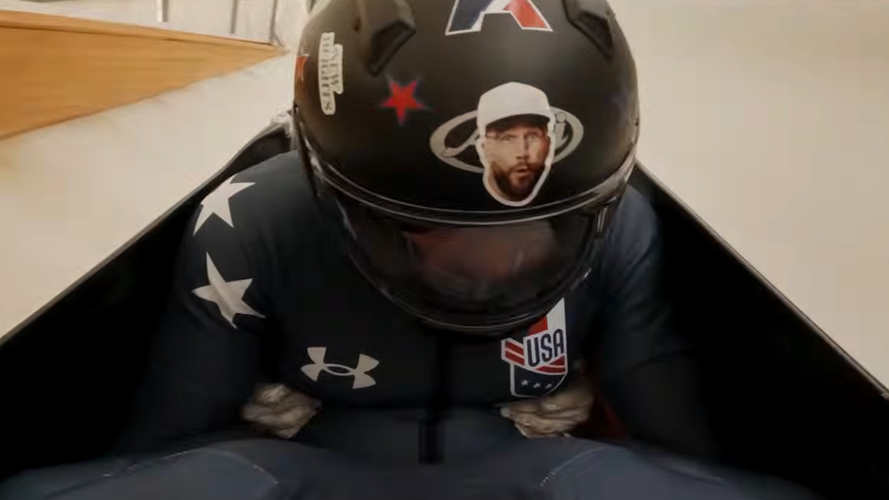 Jason Kelce rides in an Olympic bobsled with a Travis Kelce sticker on his helmet.