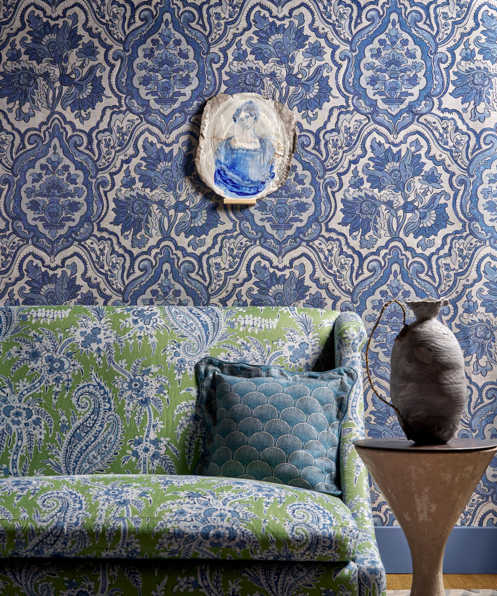 A blue room with wallpaper, a green sofa in liberty fabric
