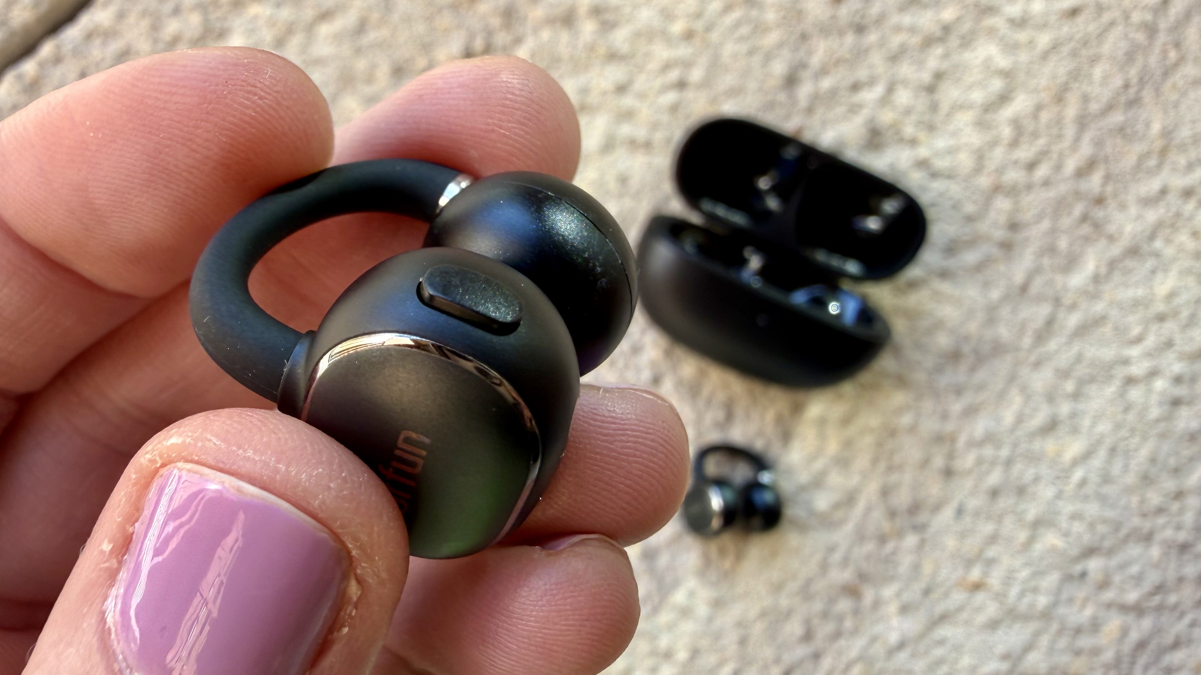 Someone holding one of the EarFun Clip 2 earbuds
