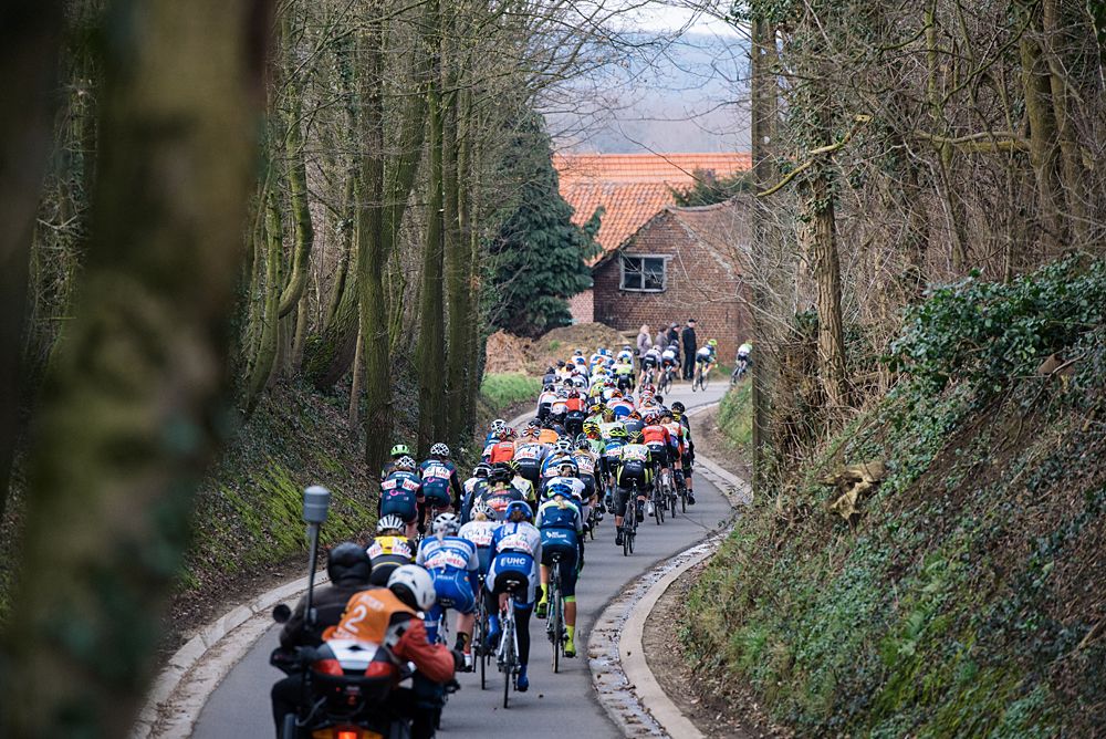 The peloton racing through narrow roads at Omloop van het Hageland