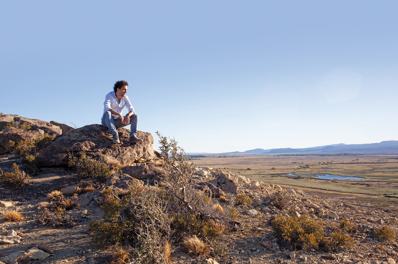 Landscape scene with man sitting on rock in Sarmiento, Patagonia, Argentina.