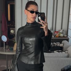 Hailey bieber wears a leather top with black sunglasses.