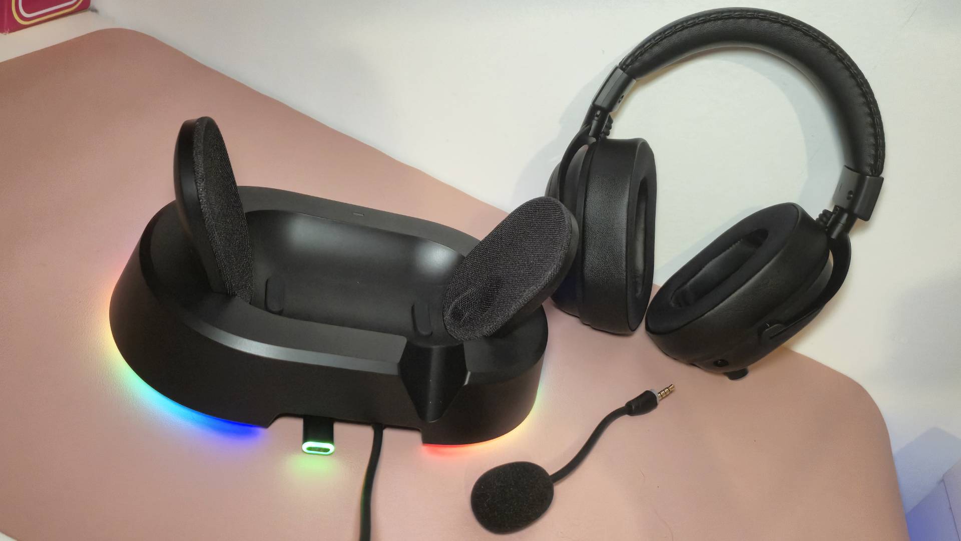 Photo of the Mchose V9 Turbo and its charging stand sitting a pink desk mat.