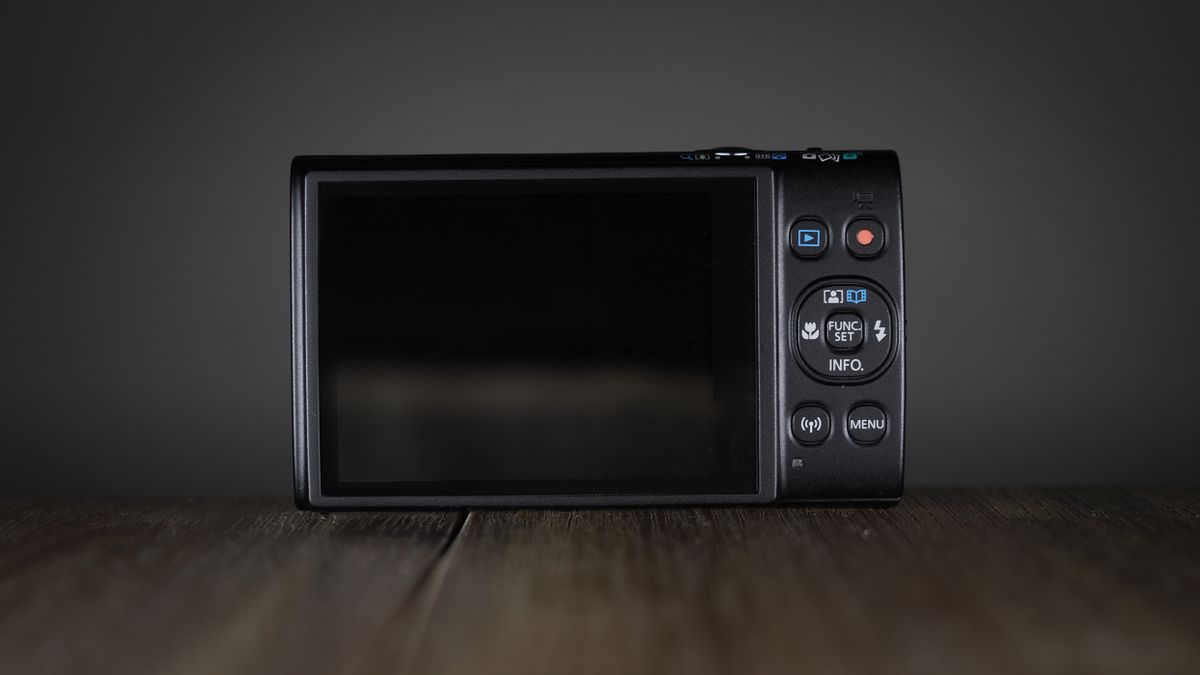 Canon Ixus 285 HS A on a wooden surface against a dark background