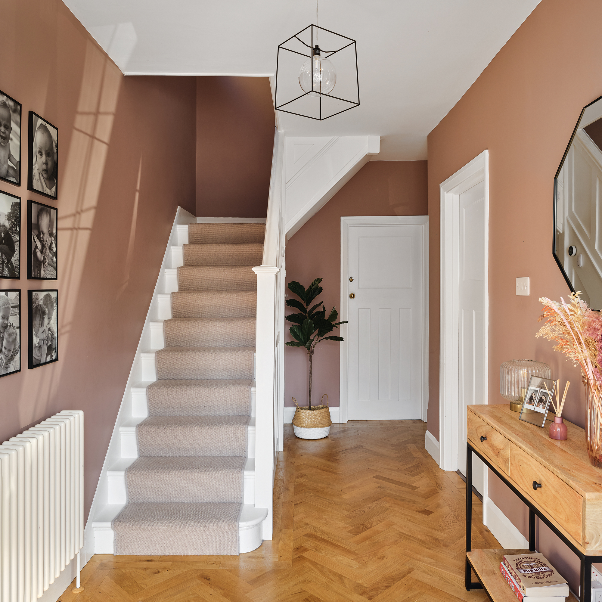 a pink hallway with parquet flooring and a carpeted stairwell