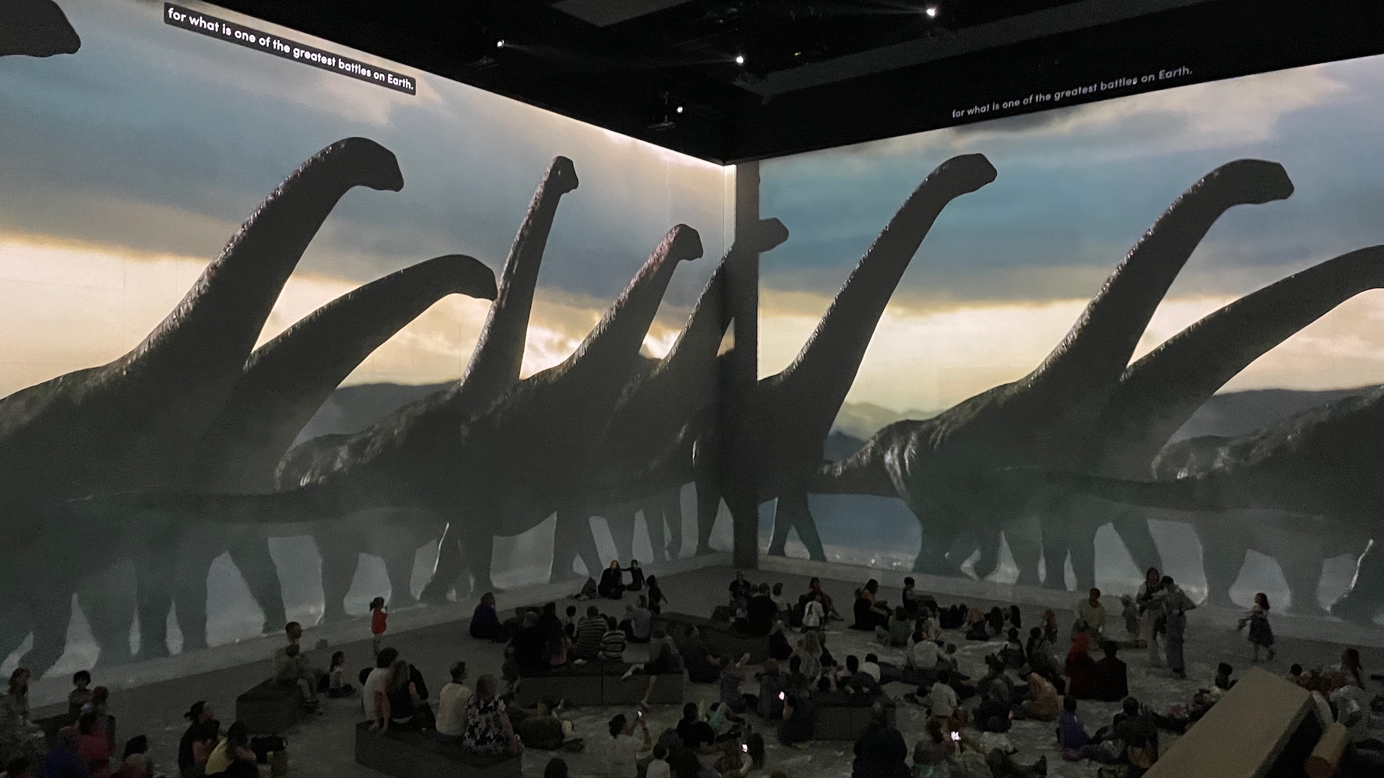 A projected image of dinosaurs roaming the landscape spanning two walls at Lightroom, Kings Cross.