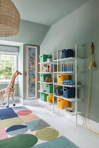 green kids room with colorful rug, giraffe toy, and open wall shelves