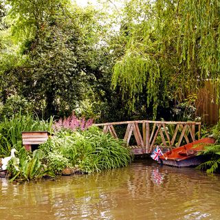 idyllic sussex farmhouse garden pond with rowing boat and ducks