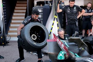 Romesh Ranganathan changing a tire in the pits for team Mercedes