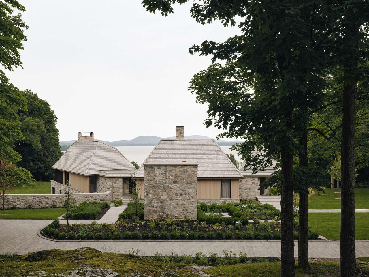 exterior of sustainable home with sprawling garden, stone walls, timber walls, and view of water