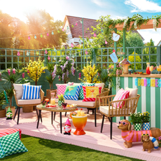 Sunny and colourful small garden with green striped bar, rattan furniture, quirky planters and bright outdoor cushions.