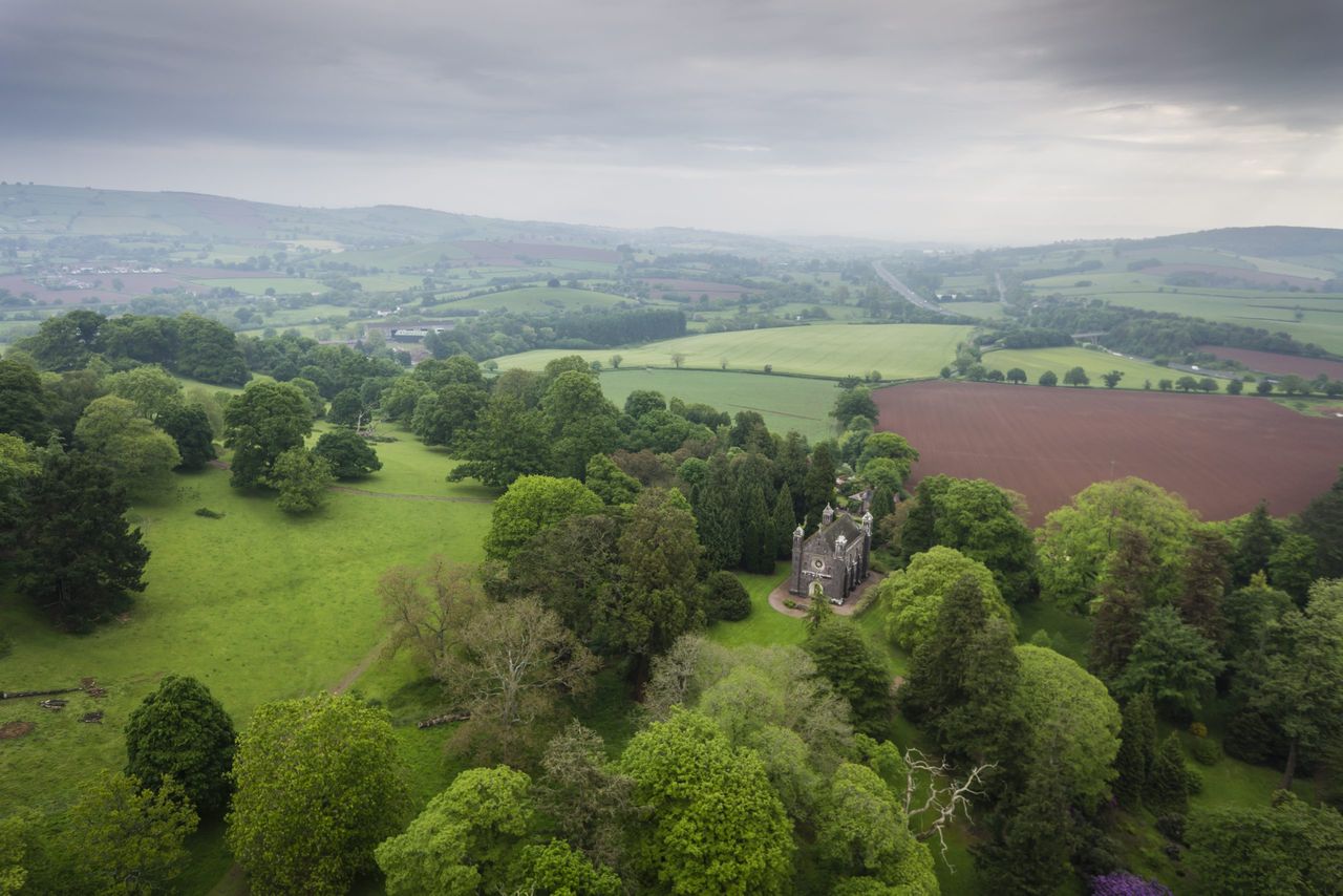 Drone shot over Killerton Chapel with large fields where new hedges will be planted to improve connectivity in background