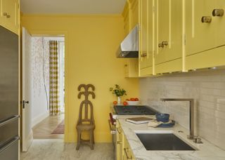 A small kitchen with yellow walls and cabinetry