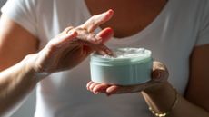 Large pot of cream in woman's hands, representing relief from what causes itchy skin