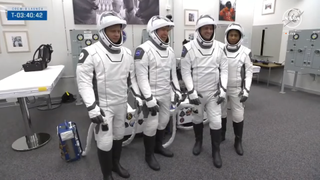 four astronauts pose for a photo in white spacesuit in a checkout room