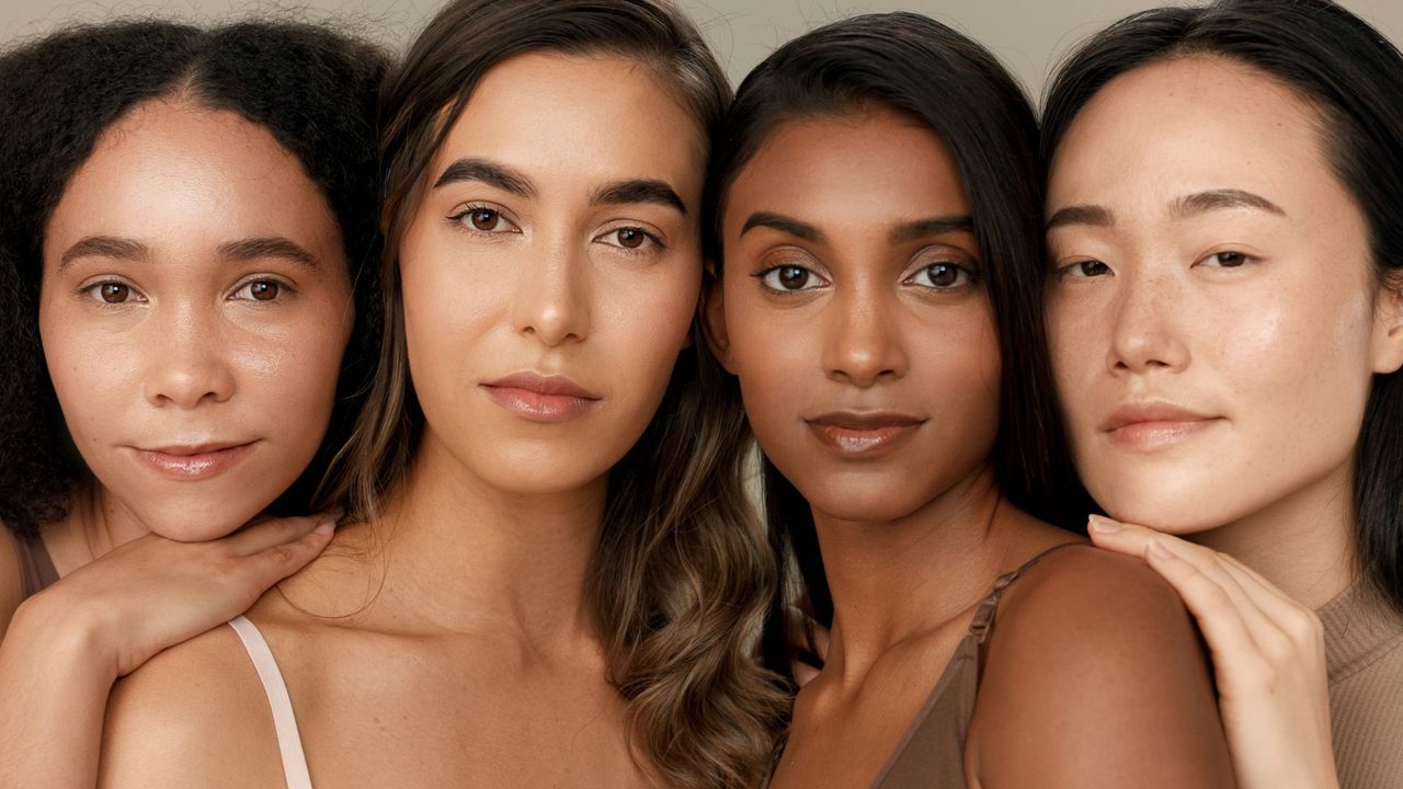 four women with fresh, bright skin smiling together at the camera