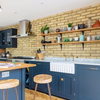view into a kitchen and kitchen island with an exposed brick wall