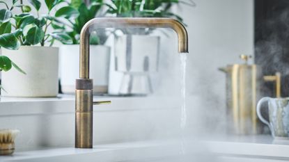 Brass boiling water tap on a white worktop, with steaming water