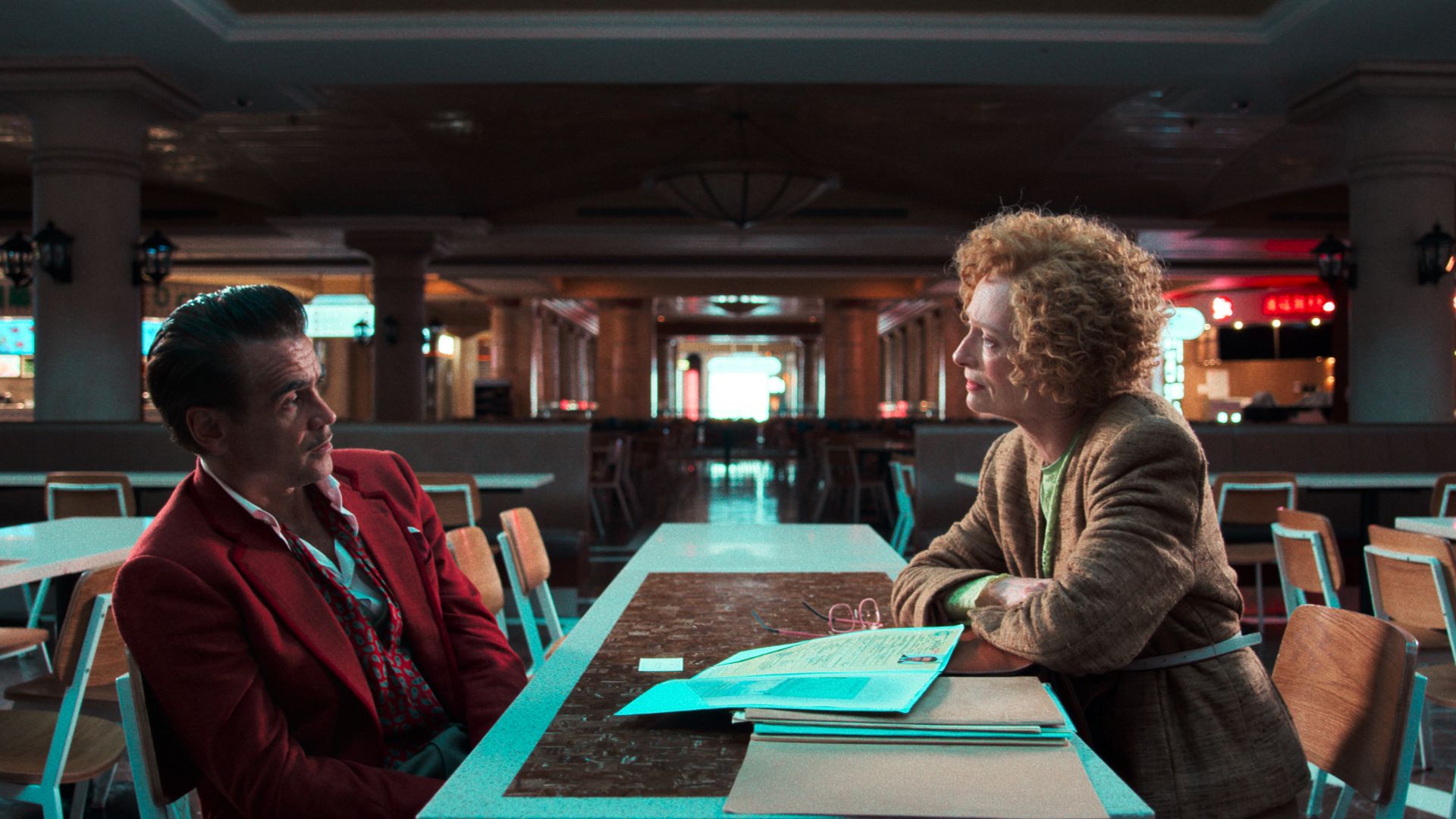 Colin Farrell and Tilda Swinton sit across from each other at a table