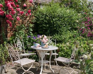 a delicate white table and chairs set in a garden, to illustrate the worst patio decorating mistakes
