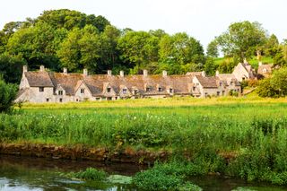 row of cotswold houses by a lake and green lawn