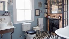 how to clean a toilet: traditional bathroom with patterned monochrome floor, light bluie walls and brick wall