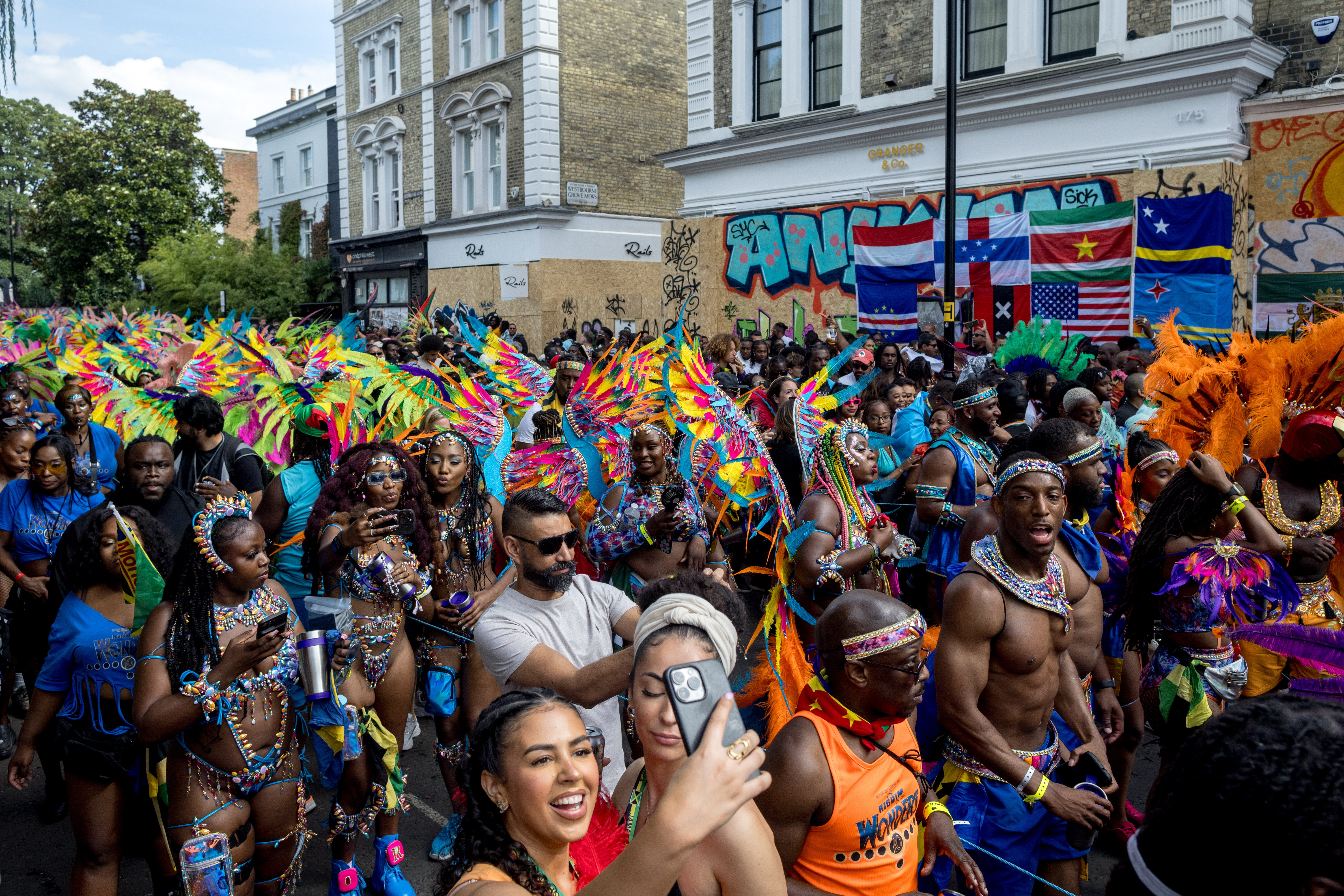 LONDON, ENGLAND - AUGUST 28: Revellers take pictures as performers parade in costume on the final day of Notting Hill Carnival on August 28, 2023 in London, England. The annual Caribbean festival, which stretches over two days, has taken place in London since 1966.