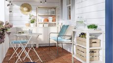 A small patio with IKEA cream outdoor storage and a white bistro set with blue cushions