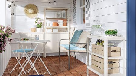 A small patio with IKEA cream outdoor storage and a white bistro set with blue cushions