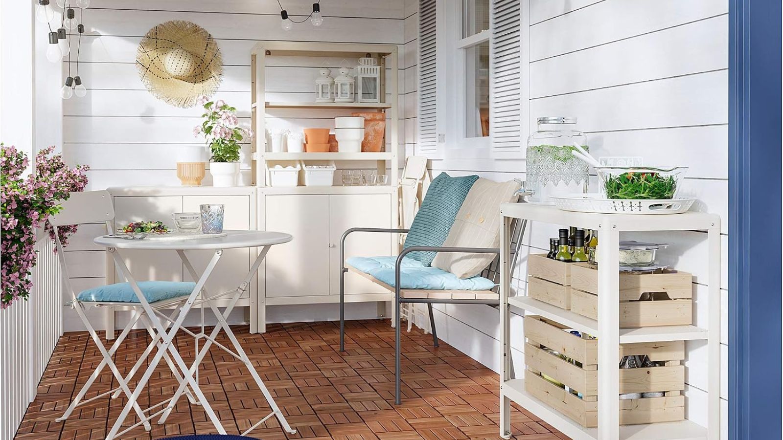 A small patio with IKEA cream outdoor storage and a white bistro set with blue cushions