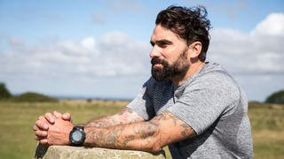 Ant Middleton standing outside with his arms on a rock