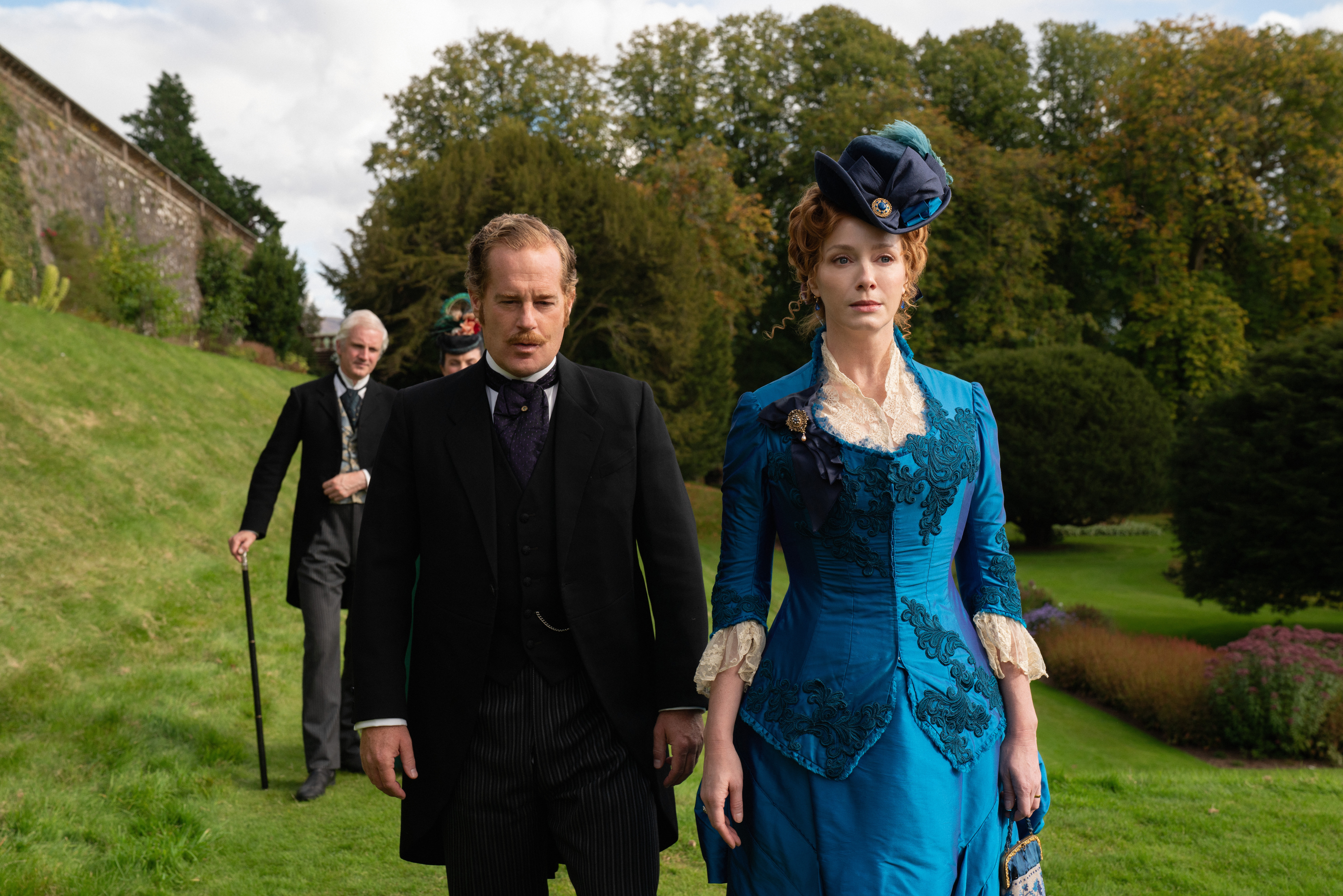 adam james and christina hendricks walking on the grounds of an estate in the buccaneers season 2