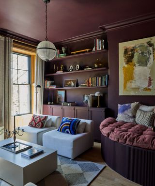 home office room with dark purple walls and ceiling, two light gray comfy chairs, built-in shelving and canvas artwork on wall