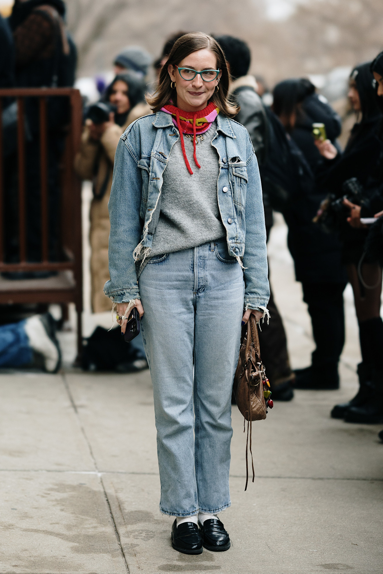 a new york fashion week attendee wearing glasses, neck tie, jean jacket, jeans, and loafers