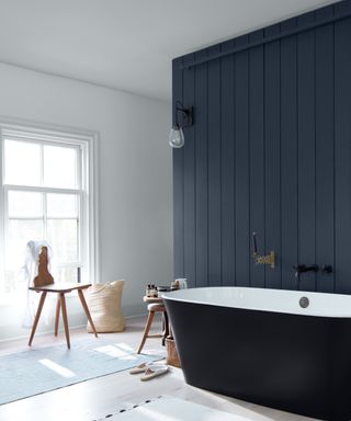 bathroom with blue panelled wall, blue sided bath and white walls to side