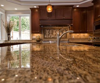 Kitchen granite counters and high end appliances with soft lighting and mix of light and dark brown shades