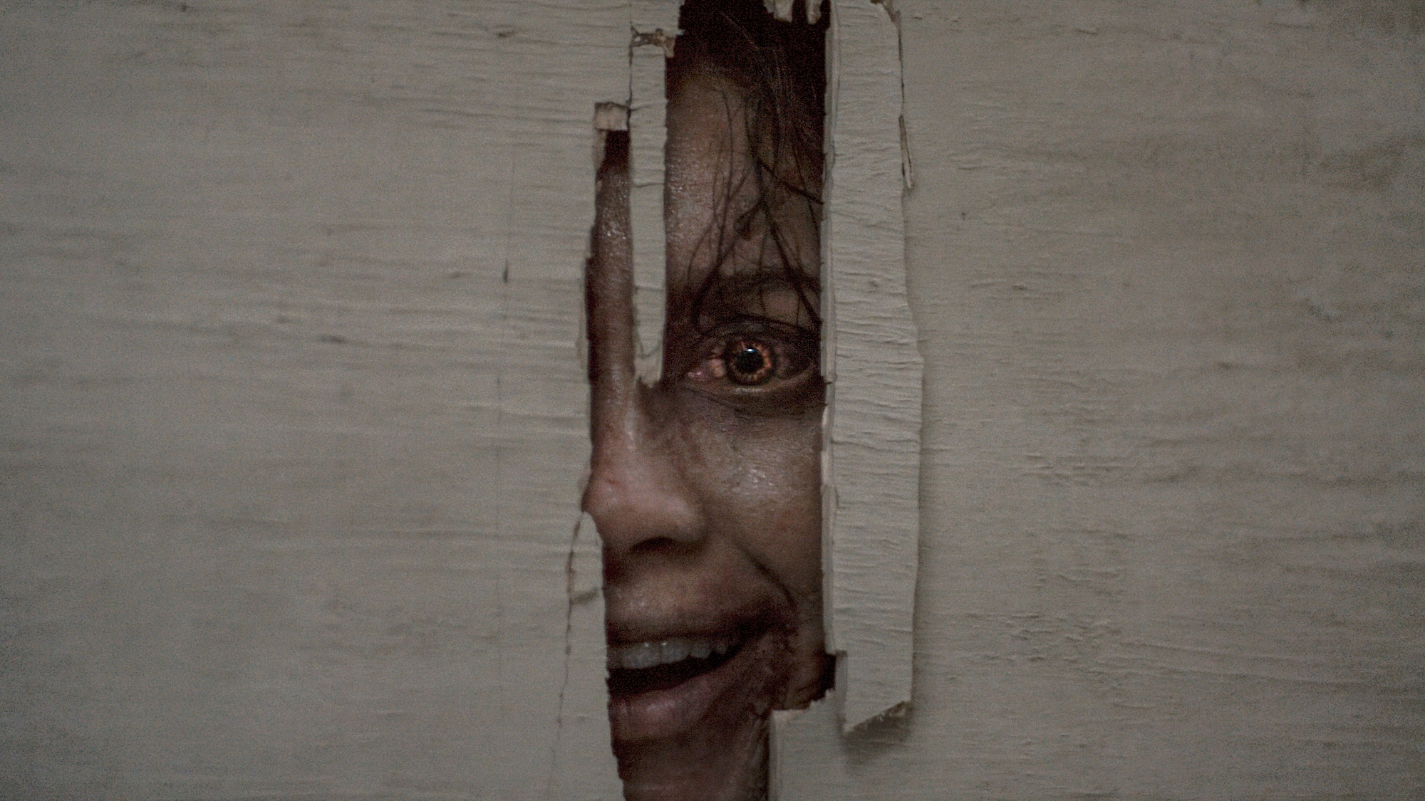 Deadite Thya's face peering through hole in a wall Shining-style in Evil Dead Burn