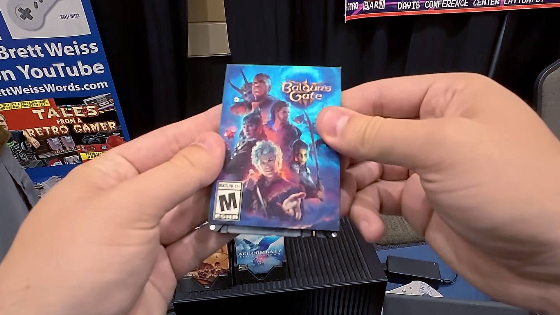 Hands holding custom Baldur's Gate PC cartridge featuring mechanical HDD and vinyl artwork.