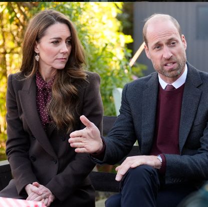 Kate Middleton and Prince William wearing maroon outfits sitting outside talking to families