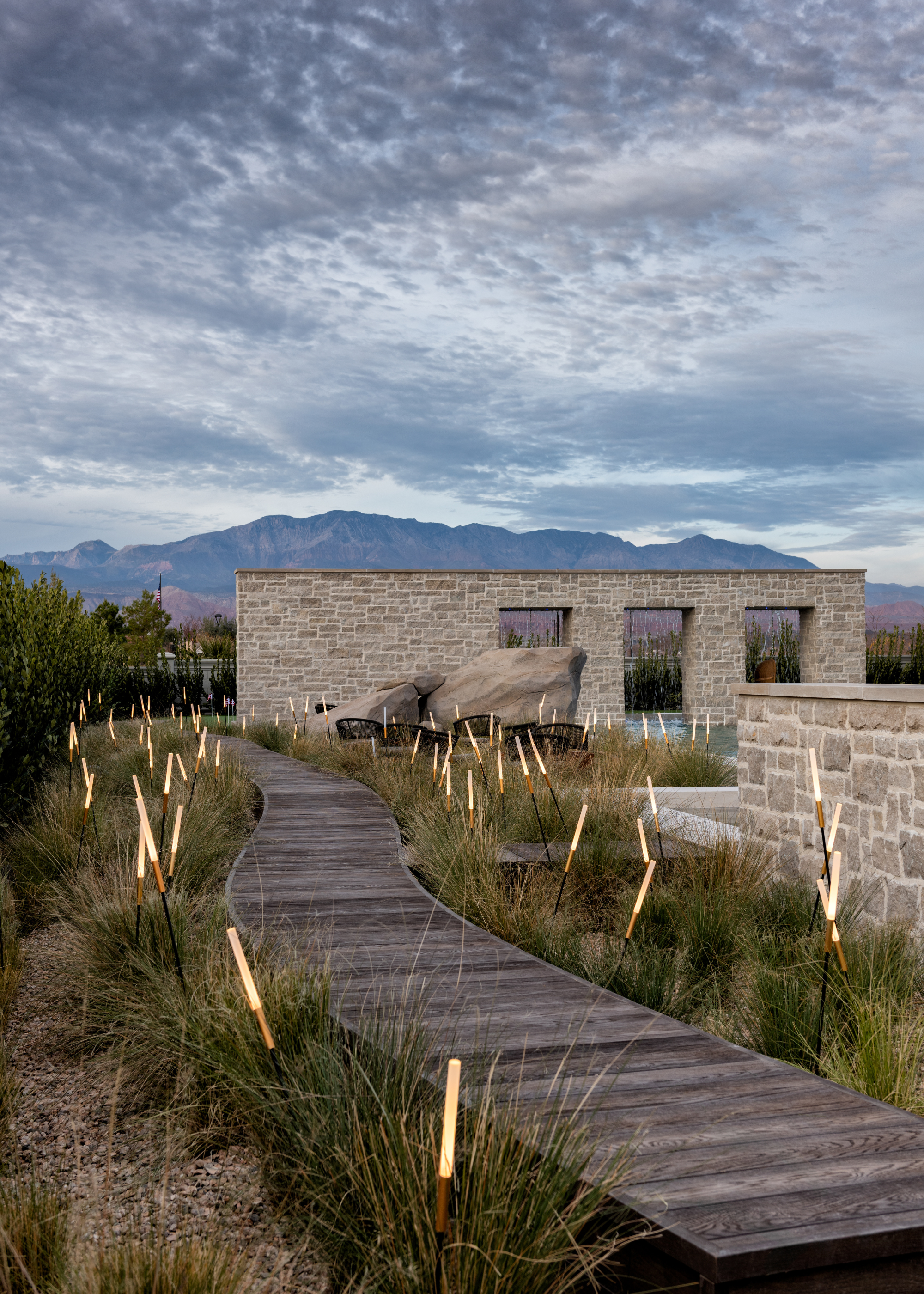 river reed-inspired uplighters lining a garden path, interspersed with ornamental grass