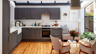 grey shaker kitchen with compact living area by a Crittal style window
