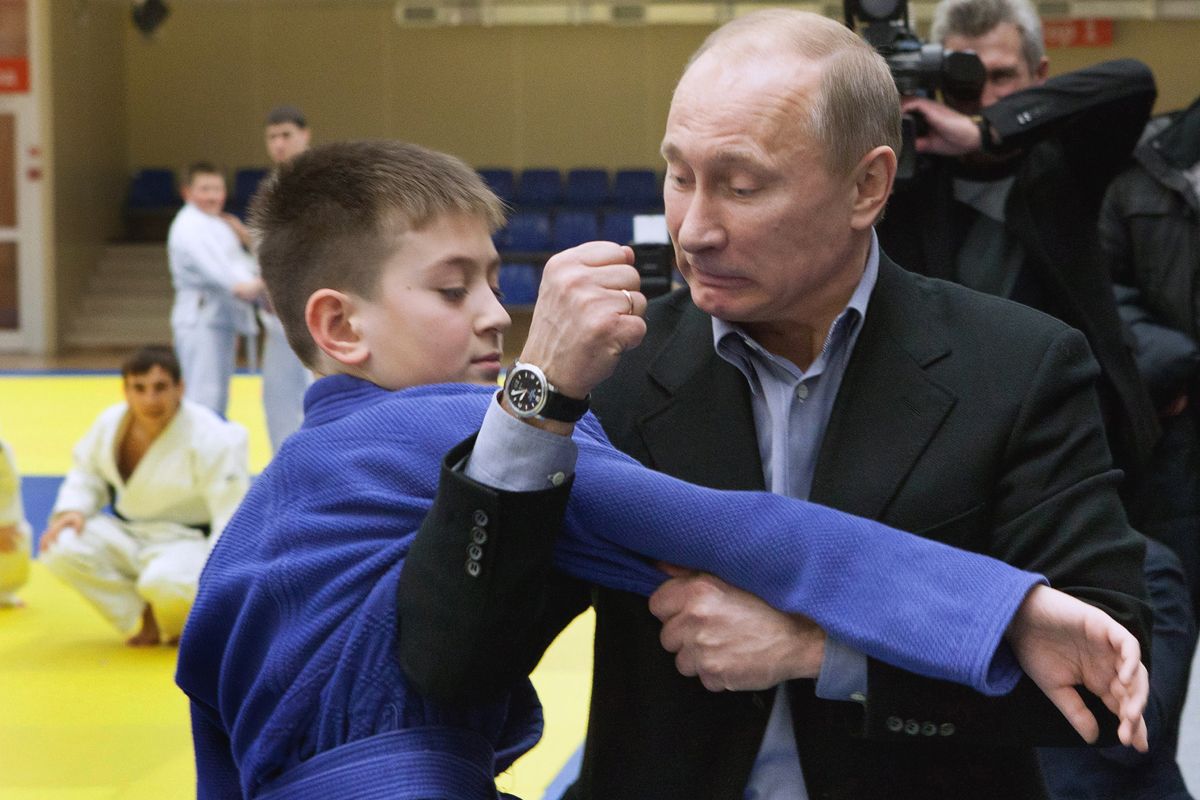 Russia's Prime Minister Vladimir Putin (R) shows a hold to a young judo wrestler at the Regional Judo Center at the Arena Sports Complex in the Siberian city of Kemerovo on January 24, 2012,