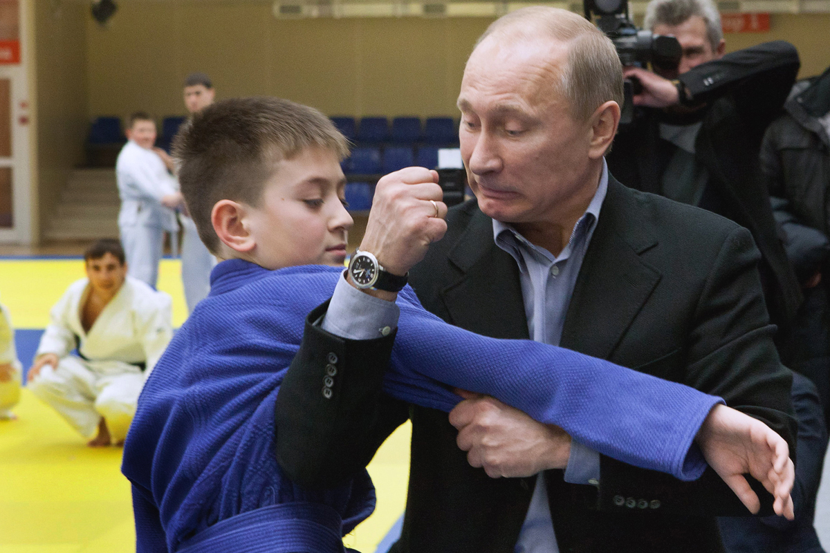Russia's Prime Minister Vladimir Putin (R) shows a hold to a young judo wrestler at the Regional Judo Center at the Arena Sports Complex in the Siberian city of Kemerovo on January 24, 2012,