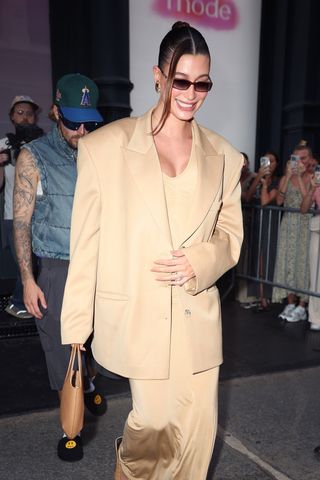 Hailey Bieber wears an oversize blazer with a slip dress and a small brown bag in new york city