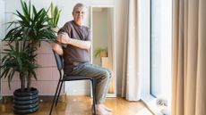Man with white hair sits in chair and twists to one side
