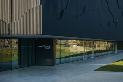 Image of Mountblanc Haus, lawn to front of building, mirrored wall leading to black door entrance, grey stone paved pathway