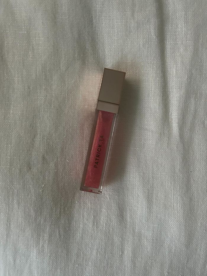 PATRICK TA Major Glow Lip Shine on a white linen background