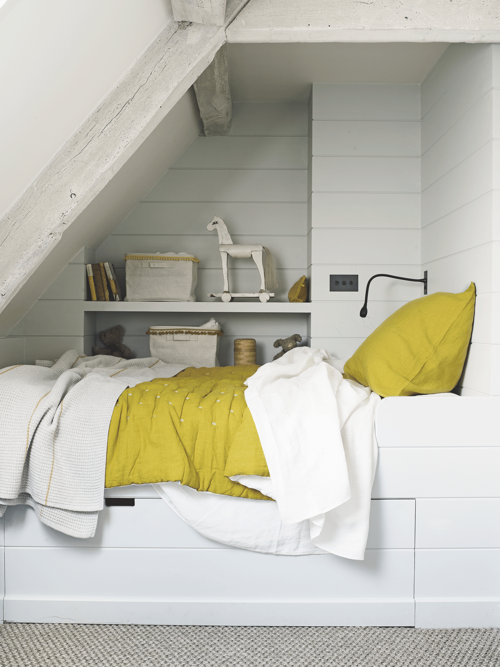 White and yellow bedroom built into the the eaves of a loft bedroom