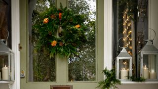 Green front door with decorative foliage wreath to show beautiful outdoor Christmas decorating idea