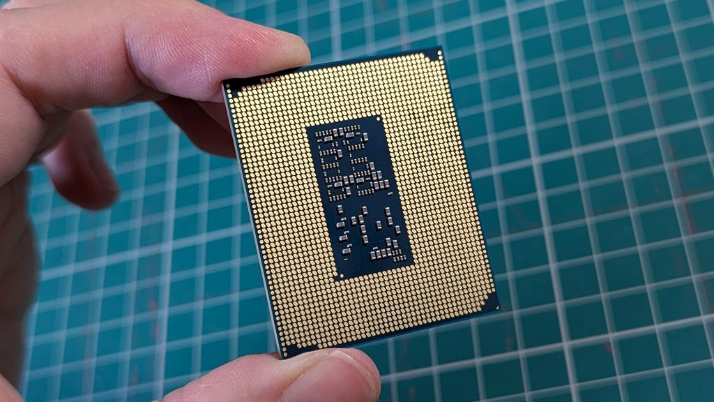 Intel Core Ultra 5 245K processor held in front of a green cutting mat showing gold connectors